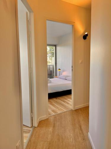 une porte ouverte menant à une chambre avec un lit et un miroir dans l'établissement Grenouille, à Dinard