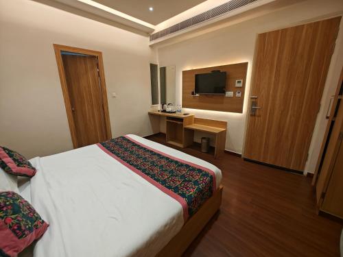 a hotel room with a bed and a desk and a television at Hotel Luxurio - In-House Barista Cafe, Near Golden Temple Amritsar in Amritsar