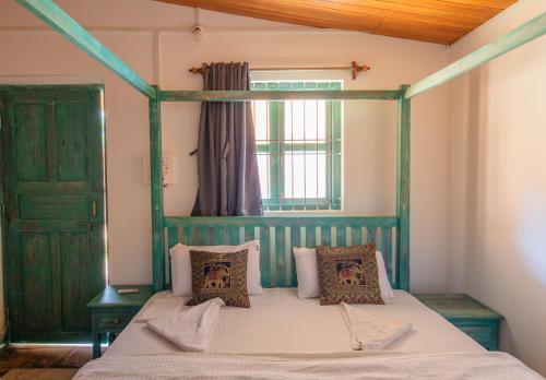 a bedroom with a green canopy bed with pillows at Radhika Eco Resort(Odonata) in Arambol