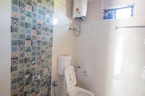 a bathroom with a toilet and tiles on the wall at Radhika Eco Resort(Odonata) in Arambol