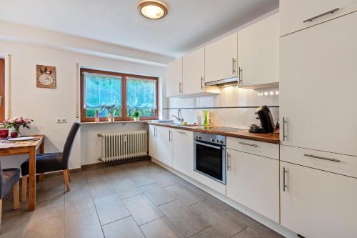 a kitchen with white cabinets and a table and a dining room at Ferienwohnung Sägegasse, Typ A in Münstertal