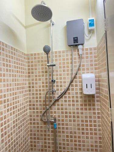 a shower in a bathroom with brown tiled walls at Baan Mali one in Hua Hin