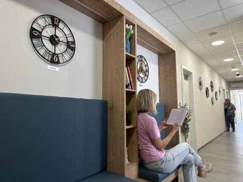 a woman sitting on a bench under a clock at Hostel Petra Marina in Dubrovnik