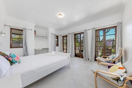 a white bedroom with a large white bed and chairs at KozyGuru | Thornleigh | Charming Two-Bed Townhouse in Thornleigh