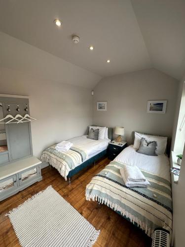 two beds in a room with wooden floors at The Courtyard Rooms in Brightlingsea