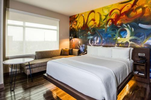 a bedroom with a large white bed and a painting at Cambria Hotel McAllen Convention Center in McAllen