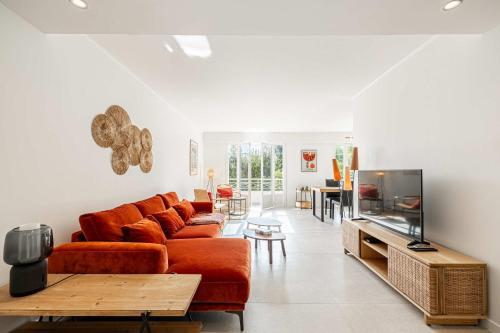 un salon avec un canapé et une télévision à écran plat dans l'établissement LE GRAND BOIS élégant et chaleureux avec balcon, au calme et à deux pas du centre-ville, à Cannes