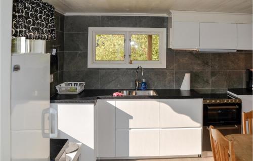 a kitchen with white cabinets and a black counter top at Stunning Home In Fristad With Wifi in Tämta