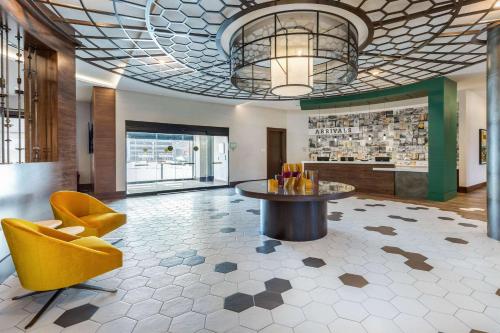 a lobby with a table and a yellow chair at Cambria Hotel - Arundel Mills BWI Airport in Hanover