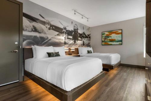 two beds in a hotel room with a painting on the wall at Cambria Hotel - Arundel Mills BWI Airport in Hanover