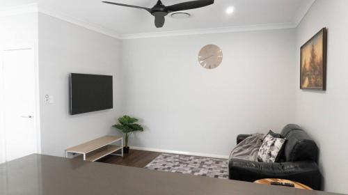 a living room with a black couch and a flat screen tv at Luxury 4 Bedroom Home - Sleeps 10 Guests in Gledswood Hills