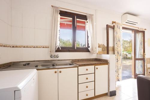 a white kitchen with a sink and a window at Villa Juana in Can Picafort