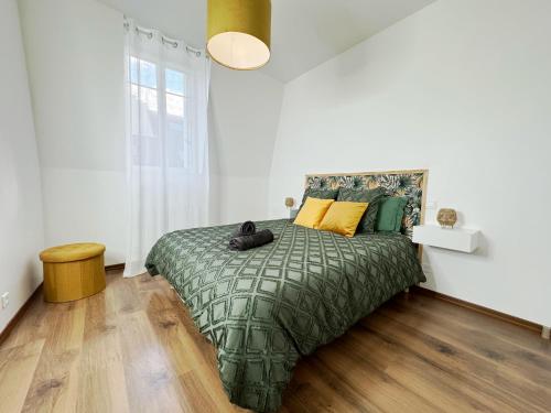 - une chambre avec un lit doté d'une couverture verte et d'oreillers jaunes dans l'établissement Nest in Heart of Épernay, à Épernay