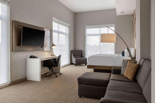 a hotel room with a bed and a couch and a desk at Cambria Hotel West Orange in West Orange