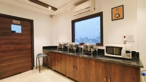 eine Küche mit einer Theke mit einer Mikrowelle und einem Fenster in der Unterkunft Hotel Tango Traxx in Amritsar