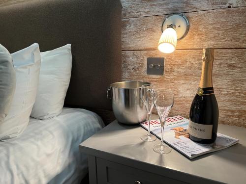 a bottle of champagne and glasses on a table next to a bed at New Flying Horse Inn in Wye