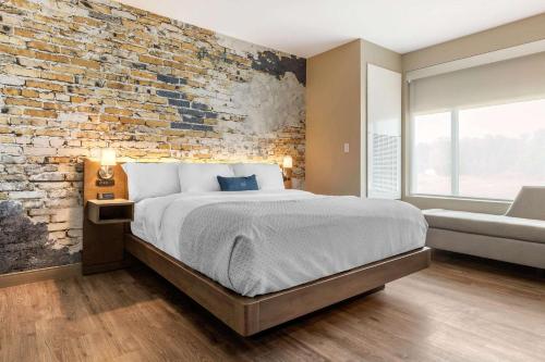 a bedroom with a brick wall and a bed at Cambria Hotel Fort Mill in Fort Mill