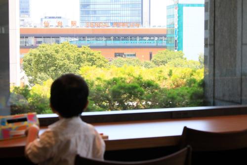 a young child looking out a window at a city at Richmond Hotel Premier Sendai Ekimae in Sendai
