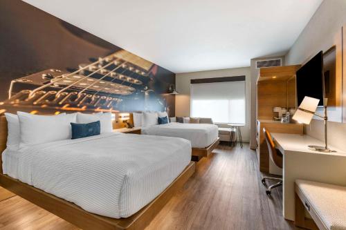a hotel room with two beds and a desk at Cambria Hotel Austin Airport in Austin