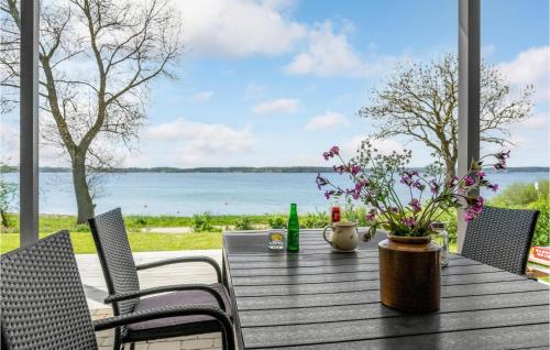 a wooden table with chairs and a table with flowers at 2 Bedroom Amazing Home In Aabenraa in Aabenraa