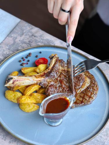 a person cutting a piece of meat with a fork and knife at Praga Hotel in Tashkent