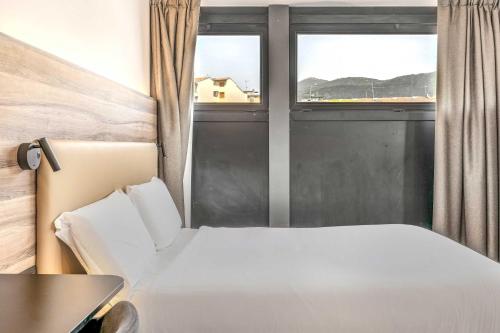 a bedroom with a white bed and a window at B&B HOTEL Prato City Center in Prato