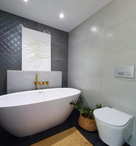 a bathroom with a white tub and a toilet at Santo Villa in Santo Estêvão