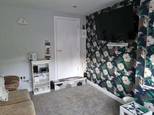 a living room with a television on a wall with flowers at Studio Near Beach Garden Parking PetsOK in Sunderland