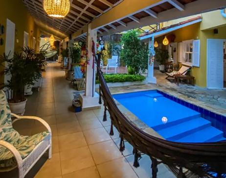 a swimming pool with a hammock in a house at Canto das Laranjeiras MOA in Guarujá