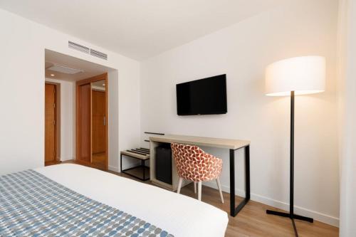 a hotel room with a bed and a desk and a television at Exe Vienna in Vienna