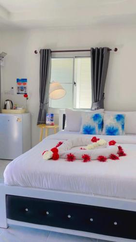 a large white bed with red flowers on it at The White House Pakbara in Ban Pak Ba Ra