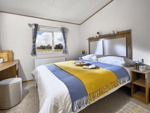 una camera da letto con un grande letto con una coperta gialla e blu di Ivy Caravan 2 at Pease Bay Leisure Park a Cockburnspath