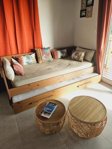 a bed with a wooden frame and two tables at Ti Oasis SEAVIEW, Studio Vue Mer à 150m de la plage in Corps de Garde