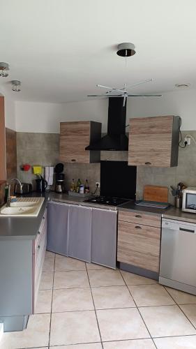 une grande cuisine avec des appareils électroménagers en acier inoxydable et des placards en bois dans l'établissement Le gîte de Santrop - 1km de la plage - Lac de Saint-Pardoux - Proche A20, à Razès