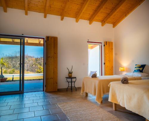 a bedroom with two beds and a view of a pool at Choeiro Verde - Casa de Campo na Costa Vicentina in Brejao