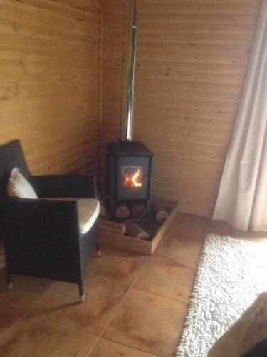 a fireplace in a room with a couch and a chair at B&B Shambala HN in Pelarco