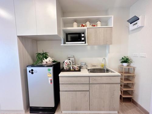 a small kitchen with a refrigerator and a sink at AVALYN Room Plus III - East Ville in Ban Hua Khao Sammuk