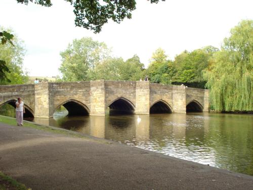a man standing in front of a bridge over a river at Castle Inn by Greene King Inns in Bakewell