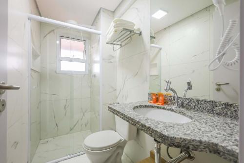 a white bathroom with a sink and a toilet at Tri Hotel Praia Grande in Praia Grande
