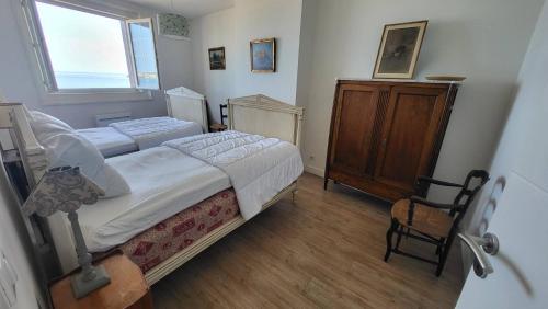 une chambre avec deux lits et une armoire en bois dans l'établissement Saint-Jean de Luz, appartement vue mer 4 couchages, à Sainte-Barbe