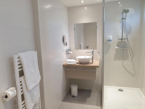 a white bathroom with a sink and a shower at Hotel Le Lion D'Or et Restaurant La Table Du Lion in Bayeux