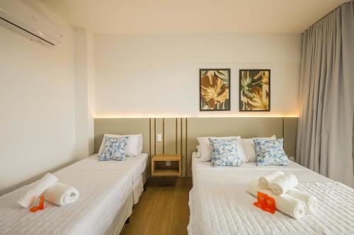 two beds in a hotel room with towels on them at Tri Hotel Praia Grande in Praia Grande