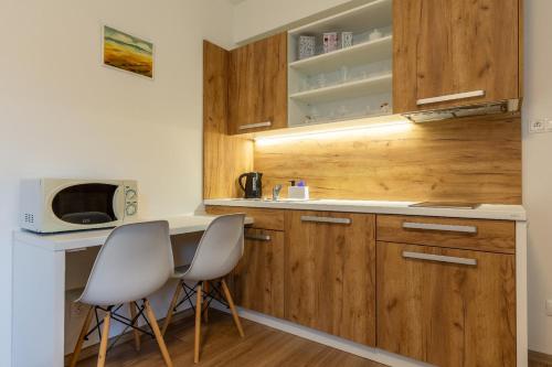 a kitchen with wooden cabinets and two white chairs at Apartmánový dom Štiavnica in Liptovský Ján