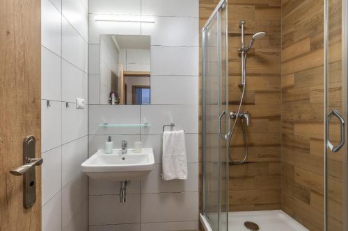 a bathroom with a sink and a glass shower at Apartmánový dom Štiavnica in Liptovský Ján