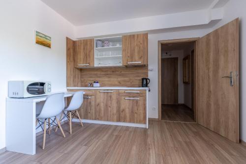 a kitchen with wooden cabinets and a table and chairs at Apartmánový dom Štiavnica in Liptovský Ján