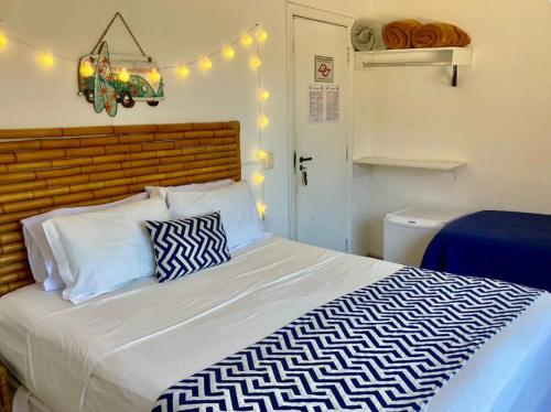 a bedroom with a large white bed with a wooden headboard at Canto das Laranjeiras MOA in Guarujá