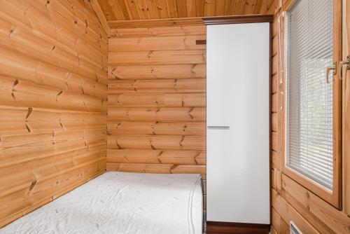 a small room with a bed in a wooden wall at Yyteri Beach Lomakeskus, Keisarinpankki 1 in Pori