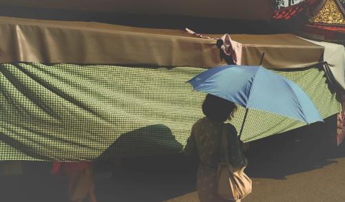a person holding a blue umbrella in front of a table at Yesterday Hotel in Chiang Mai