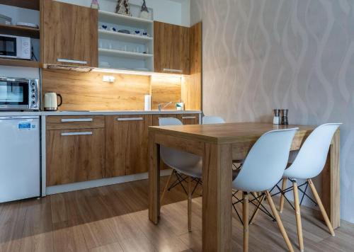 a kitchen with a wooden table and white chairs at Apartmánový dom Štiavnica in Liptovský Ján