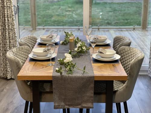 a wooden table with chairs and plates and wine glasses at Hollicarrs - White Rose Lodge in Riccall